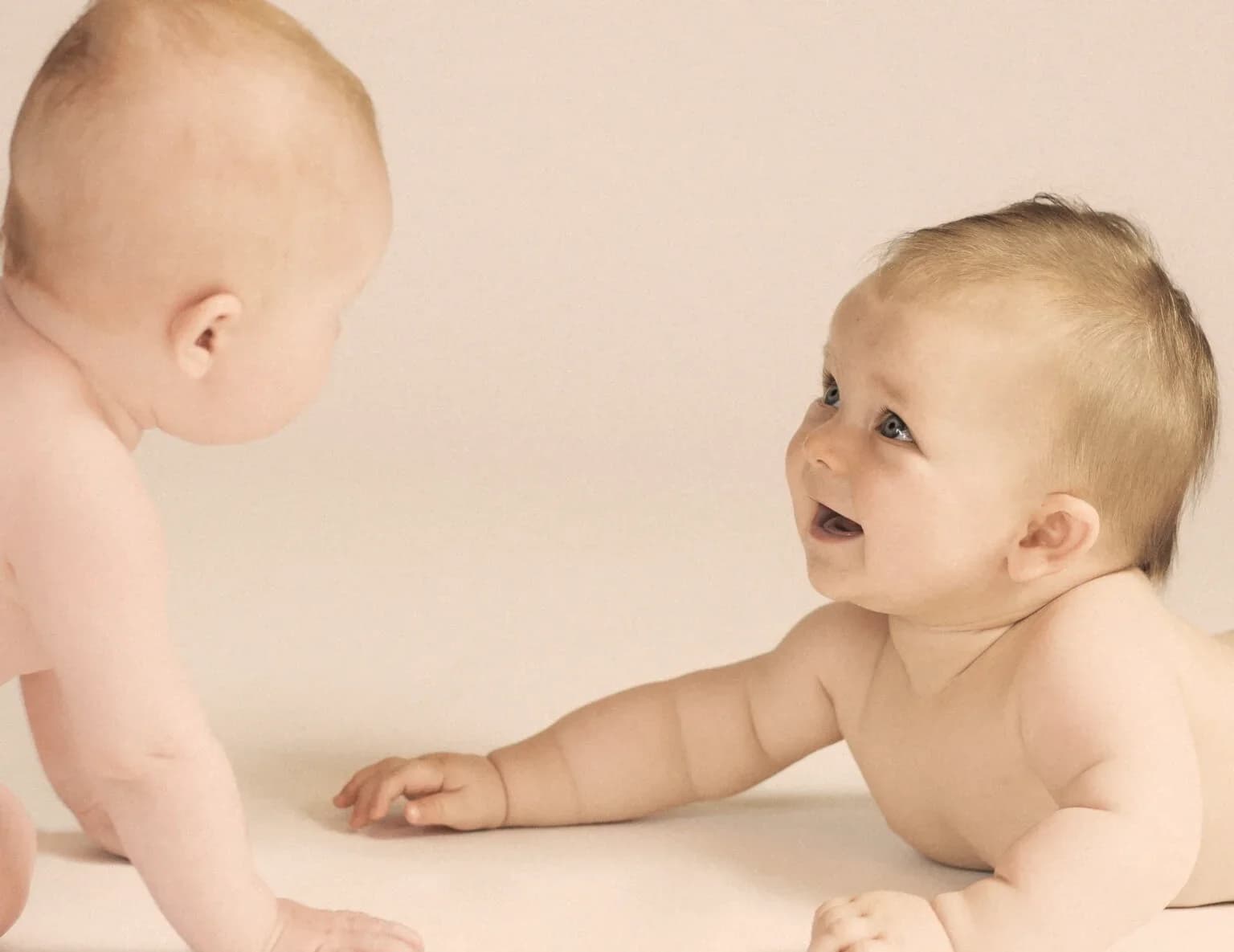 Baby in Bauchlage lächelt seine Mutter an